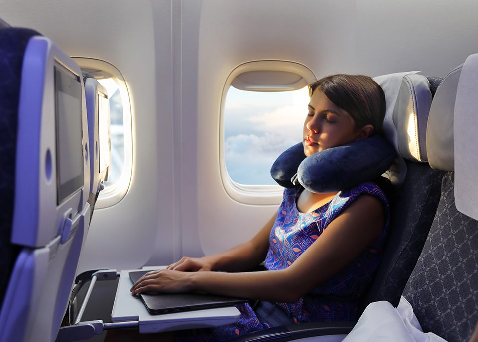 Young woman sleeps on an airplane with neck pillow